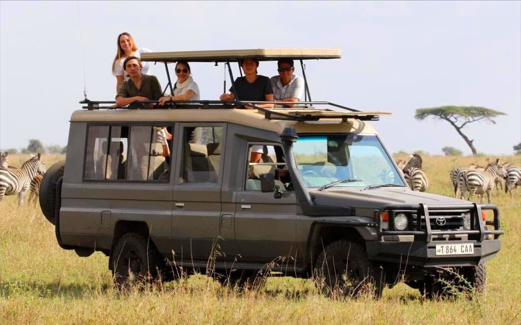 Private safari vehicle with guests viewing zebra on a Rwanda tour package